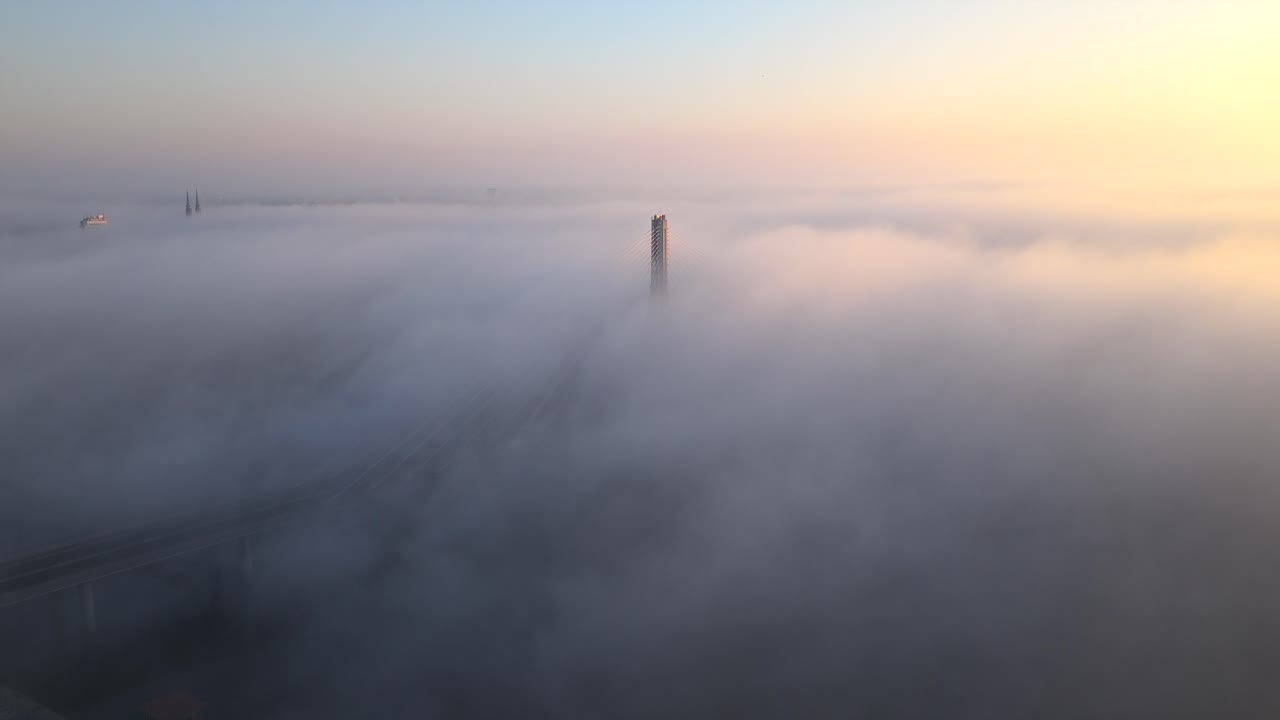 Aerial view of foggy Warsaw bridge at sunrise, serene and mysterious