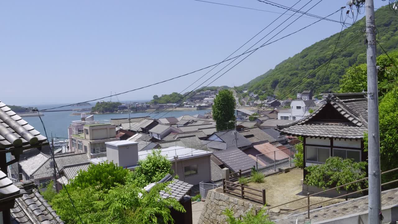 Slow motion panning shot over calm seaside town in Japan on sunny summer day