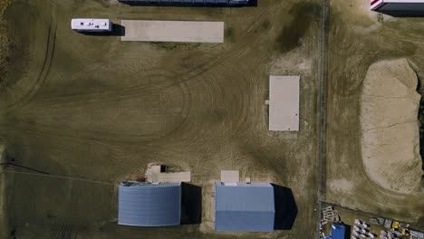 vista aérea de arriba hacia abajo de tierras agrícolas industriales llenas de almacenes, herramientas y equipos en el suroeste de manitoba, canadá