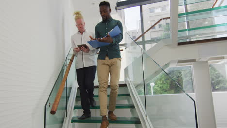 diverse businessmen walking with documents and talking in creative office