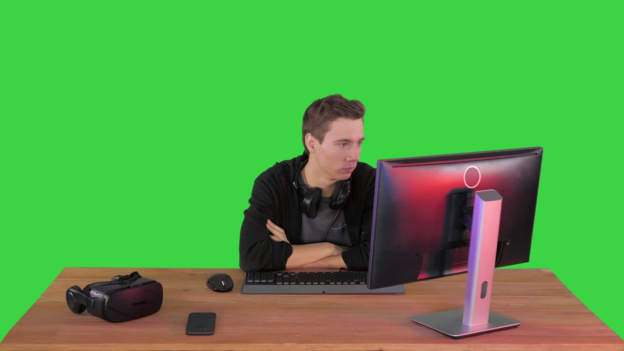 Young man gamer watching stream game on a Green Screen, Chroma Key