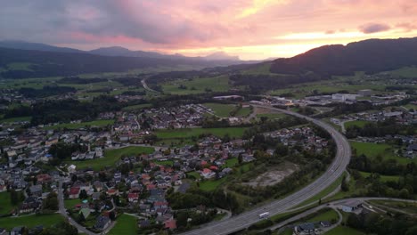 Carretera-En-Austria-Con-Cielo-Naranja-Rosado-A-Través-Del-Atardecer-Detrás-De-Las-Nubes---Aéreo