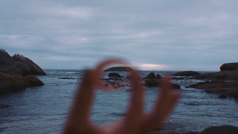 cerca de la mano sosteniendo una concha de mar en una playa costera nublada