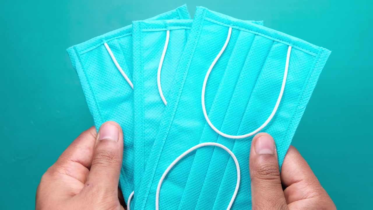 persona que sostiene varias máscaras faciales de azul azulado