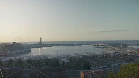 Hochauflösender-Café-Vorsprung-Mit-Blick-Auf-Den-Hafen,-Die-Skyline-Von-Barcelona,-Spanien,-Mit-Goldenem-Sonnenaufgang-In-6K,-Während-Vögel-Fliegen