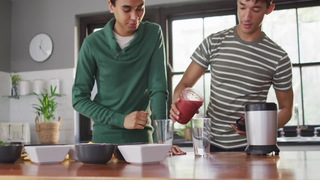 feliz pareja masculina diversa haciendo una bebida saludable juntos en la cocina