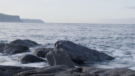 Olas-Rodando-En-Un-Rompimiento-En-Rocas-Costeras-Negras-Salpicando-Un-Espumoso