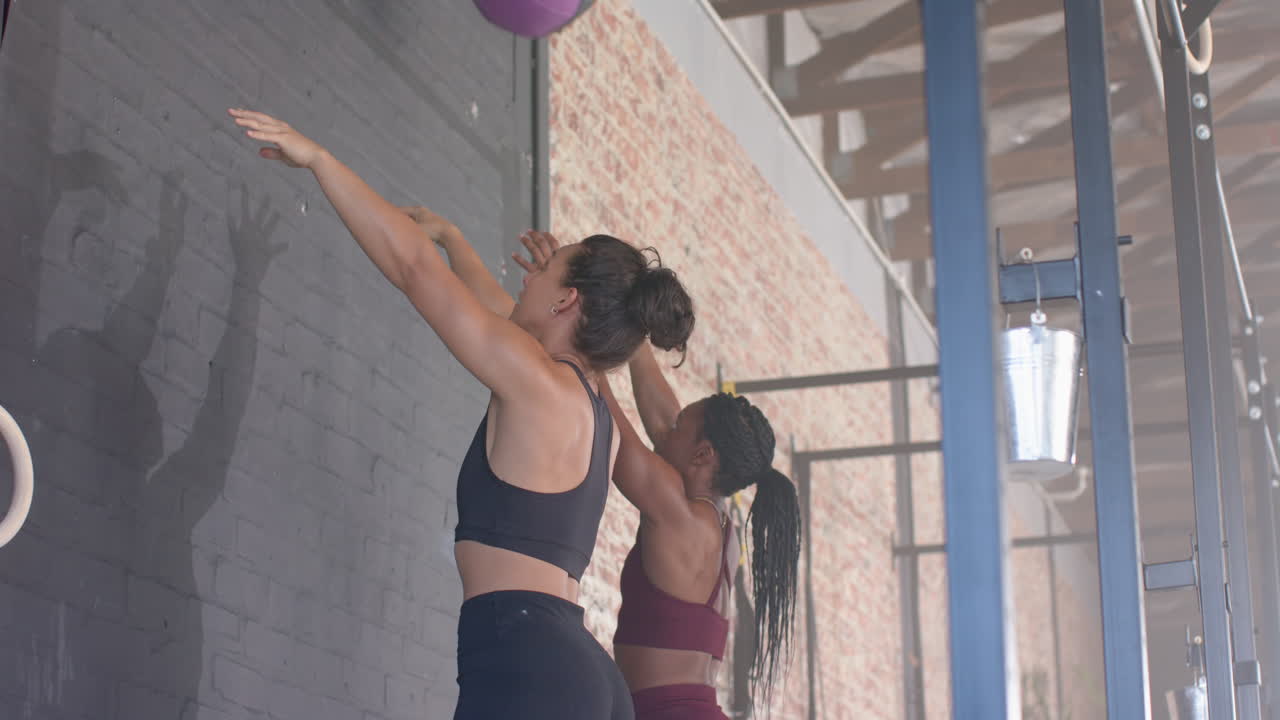 Lifting green medicine ball, women exercising together in gym for fitness training