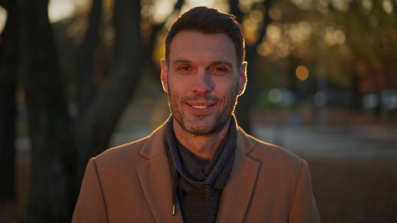 Portrait of a man in a coat and scarf in the autumn park