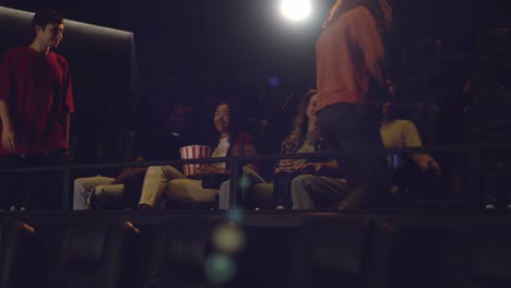 group of young friends in a movie theater, came watching a movie on a big screen