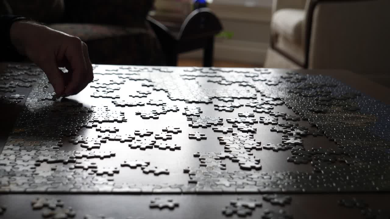 Hand Placing Puzzle Piece on Wooden Table, Strong Backlighting