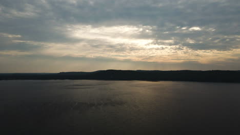 los rayos amarillos celestiales del sol cortan a través de las nubes nubladas de la tormenta extendiendo la luz sobre el lago