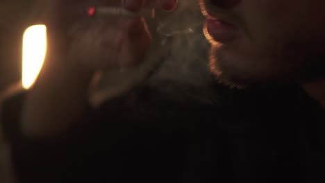 macro shot of man holding cigarrette inhaling and exhaling smoke fast nervously