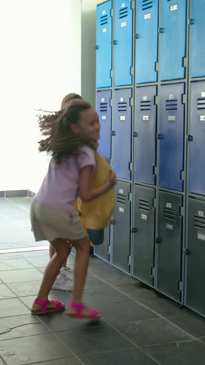 Vertical video: Running girls in lilac tee as door opens, grabbing backpacks at lockers for class