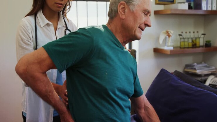 Senior erhält Rückenmassage vom Physiotherapeuten 4k