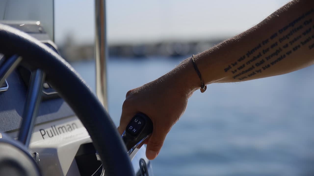 close view of a man boat captain driving and operating a small boat turning the wheel as the boat goes through the ocean