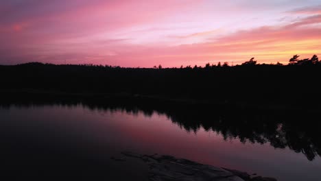 Aerial-of-lakeside-forested-sunset,-Hällingsjö,-Sweden