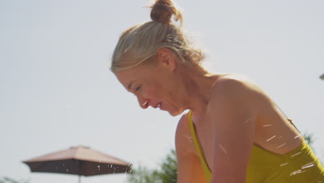 grandparents having fun with granddaughter swimming in pool on family summer holiday