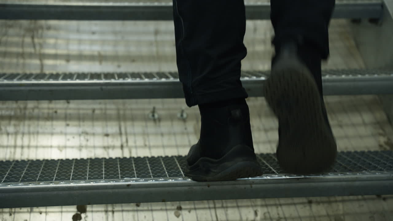 Worker ascending industrial stairs with determination. Perfect for factory or labor safety themes