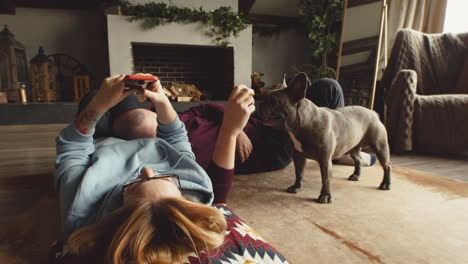 Paar-Spielt-Mit-Ihrem-Bulldoggenhund-Mit-Einem-Tennisball,-Der-Im-Wohnzimmer-Auf-Dem-Boden-Liegt