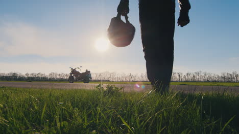 silhouette of a biker with helmet in hand looking at the motorcycle hd video