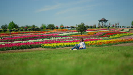 blooming spring park and young woman relaxing on fresh green grass.