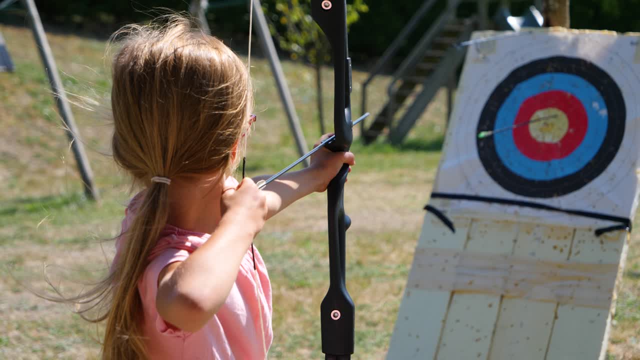 una niña pequeña perdiendo un tiro de arco en cámara lenta