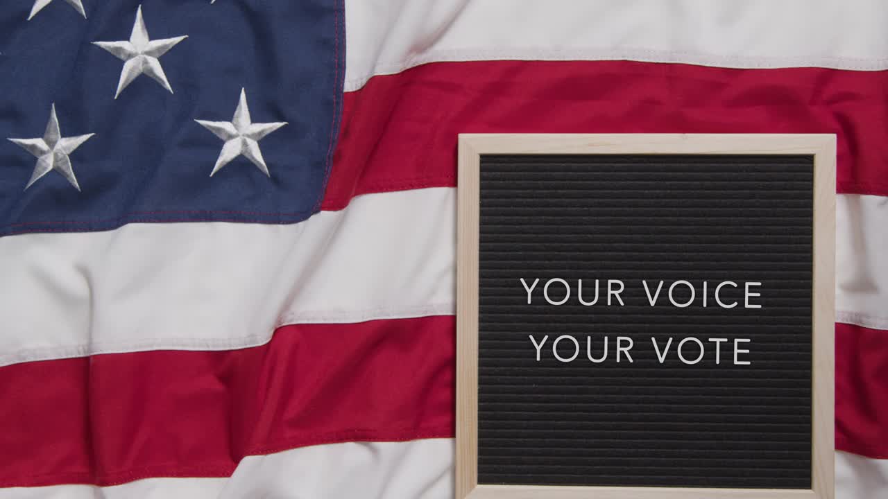 Animated Sign Spelling Out Your Voice Your Vote Lying On US Stars And Stripes Flag For American Election 2024 1