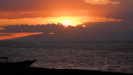 Silhouetted-traditional-fishing-boat-during-stunning-sunset-over-ocean-on-the-tropical-island-of-Timor-Leste,-Southeast-Asia