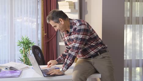hombre maduro freelance trabajando en línea desde casa en internet usando una computadora portátil.