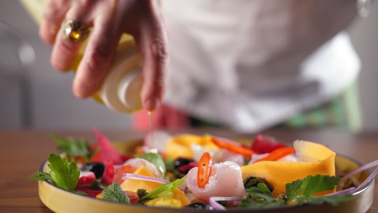 Chef with a white shirt prepares a sea bass carpaccio and puts olive oil on it - slow motion push in to focus shot
