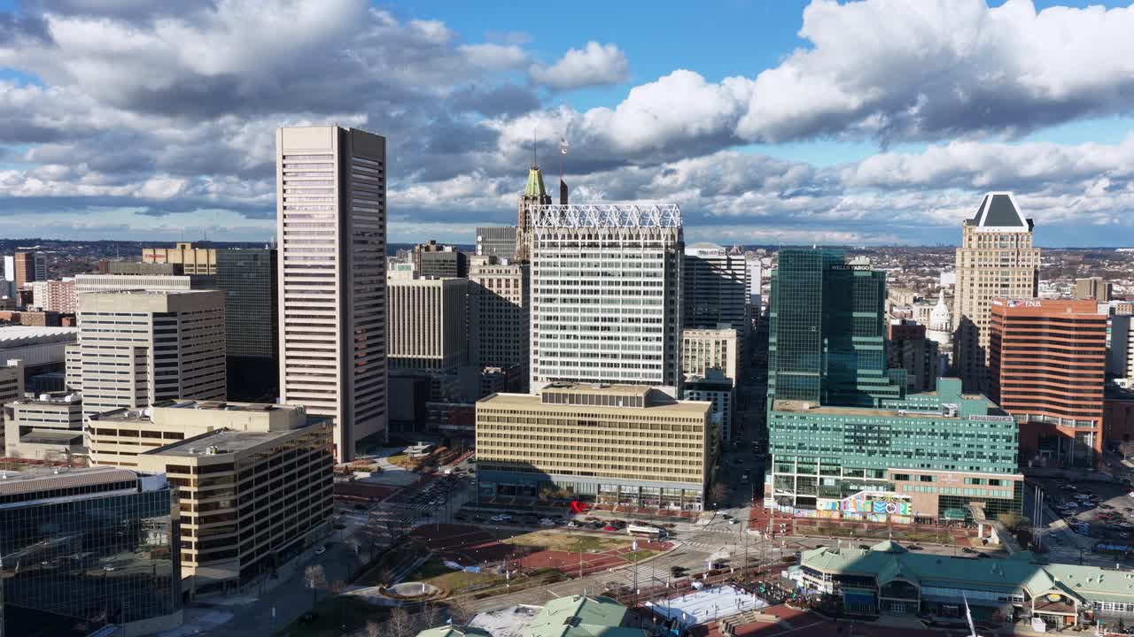 Luftfoto af Baltimores indre havn og downtown skyline, der viser højhuse, marina-anlægsbroer, attraktioner ved vandet og tætte byområder under en klar daghimmel