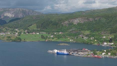mountain scenery with coastal villages near industrial harbor in vestland, norway. aerial shot