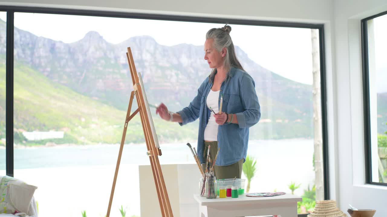 Et tomt lerret som inviterer en voksen kvinne til å gripe penselen, dyppe den i krukker og male på lerretet ved staffeliet i et atelier