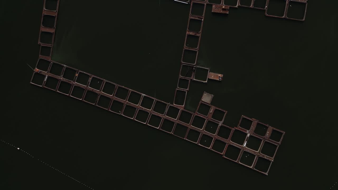 저수지의 평온한 물 위에 떠다니는 기하학적 어류 양식 구조의 공중 사진