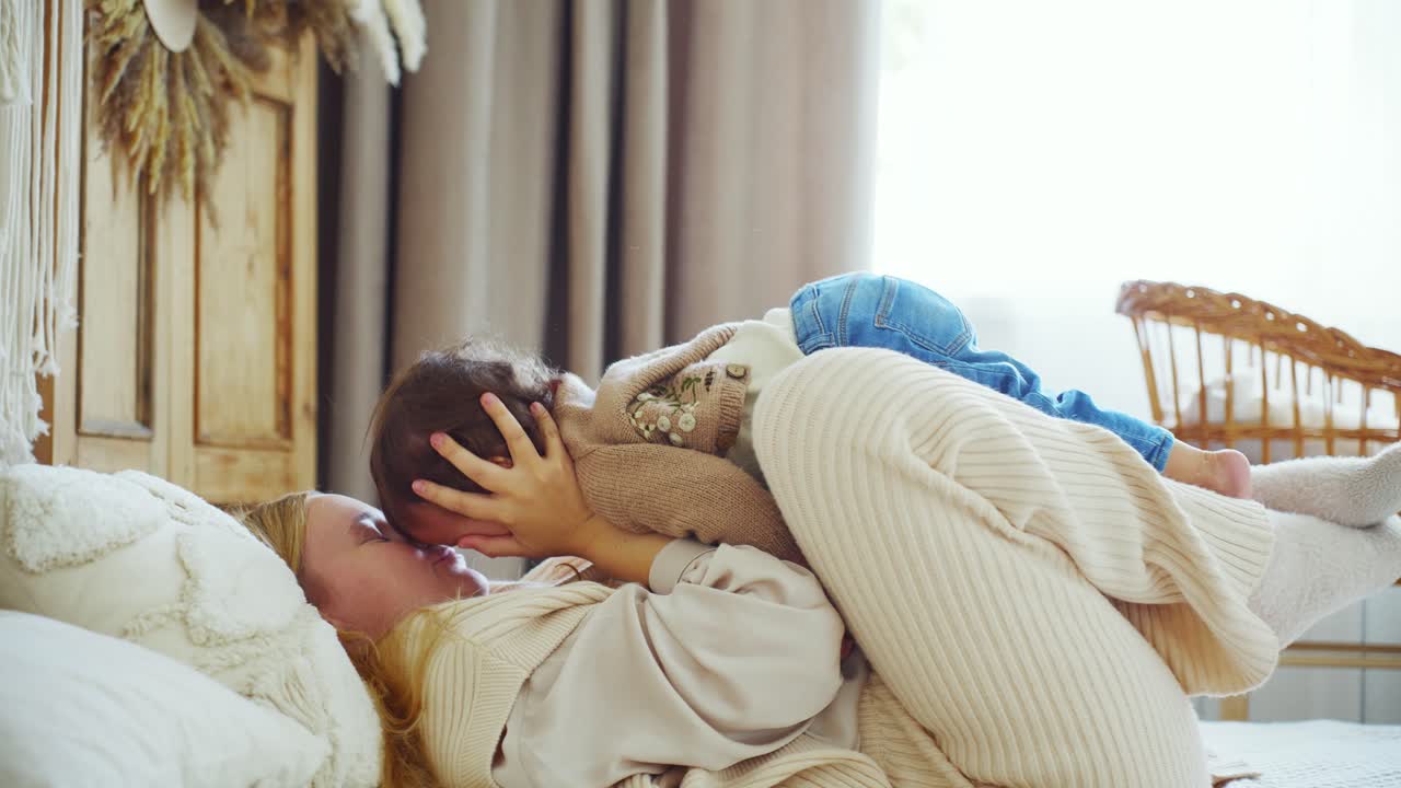Madre e bambino felici sdraiati e che giocano sul letto