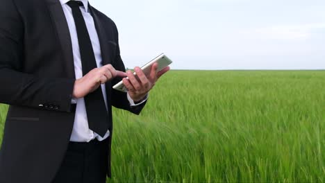 business man wearing black suit standing in office using mobile phone business man wearing black suit standing in office using mobile phone professional executive adult businessman holding smart phone in hand checking new mobile solution on cell phone close up