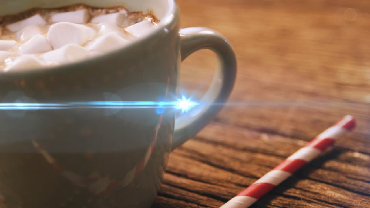 Soft blue lens flare sweeping across tabletop revealing marshmallow-topped hot cocoa in white mug