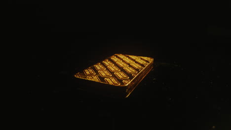 a credit suisse gold bar on a rotating platform against a black background - close up