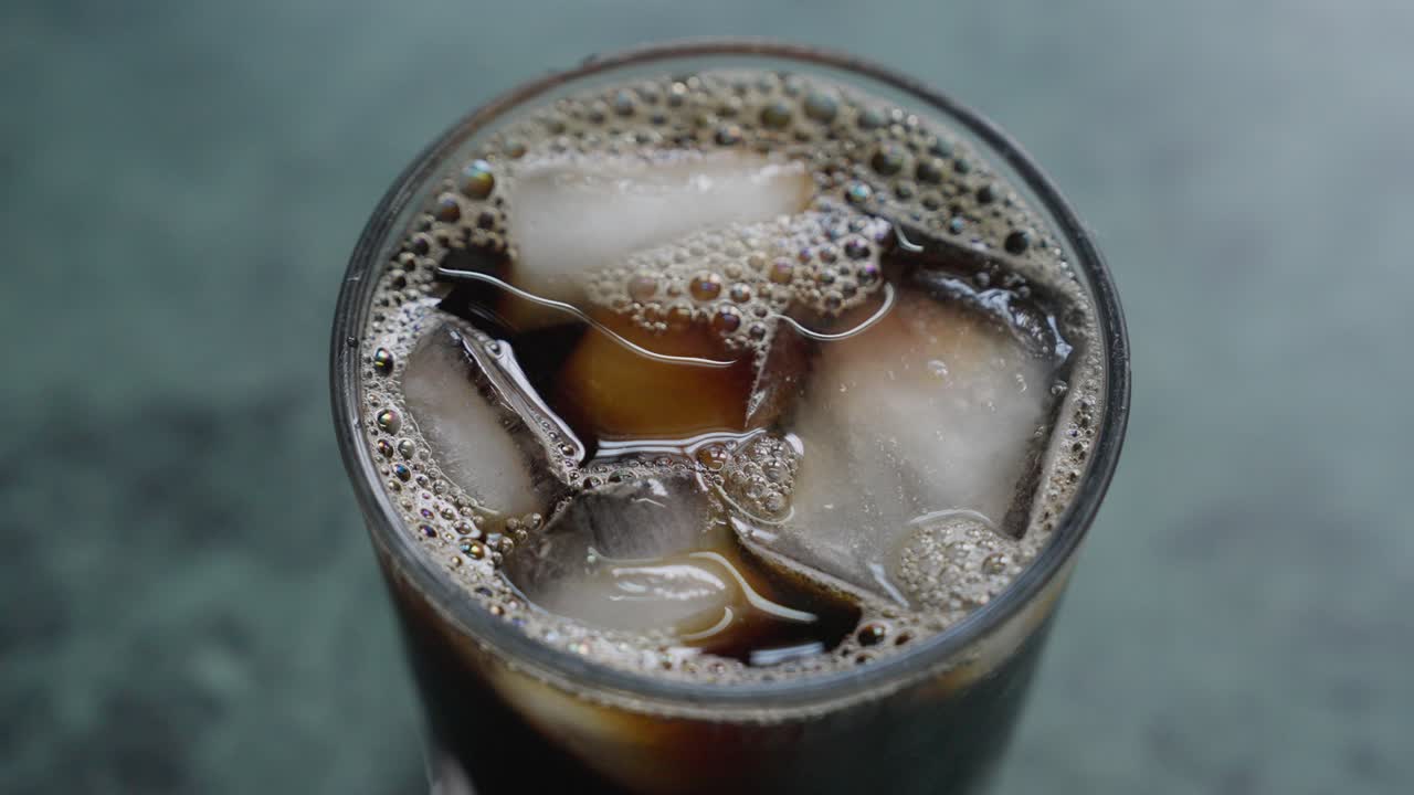 A close-up, top view of a glass of iced tea with ice cubes, with blurred background