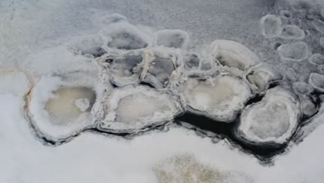 ice shape and yellow foam formation float on dark lake water, cold winter