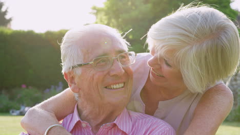 happy senior couple embrace and smile to camera in garden