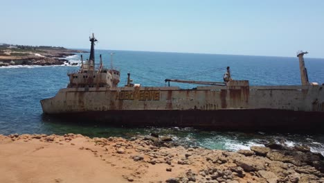 barco varado y abandonado junto a una costa rocosa en chipre, dron 4k
