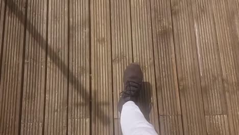 1st person view pov of man walking on wooden decking on warm sunny day