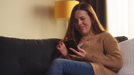 Mujer-Sentada-En-Un-Sofá-En-Casa-Viendo-Una-Película-O-Programa-O-Navegando-Por-Internet-En-Un-Teléfono-Móvil-10