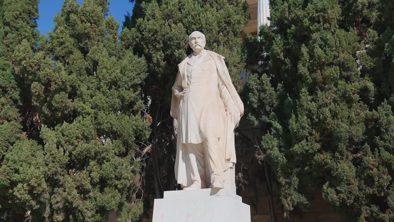 Statua di Panayia Vallianou tra alberi alti sotto un cielo azzurro e limpido