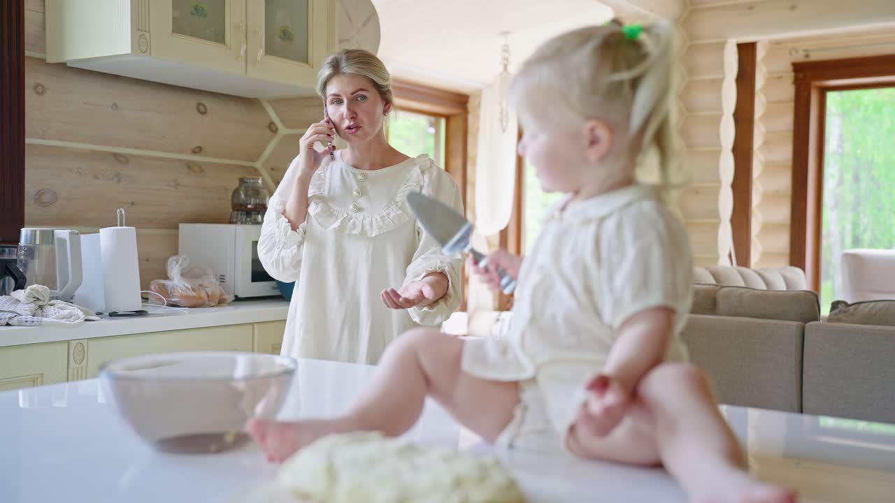 Mother talking on phone while daughter plays in the kitchen