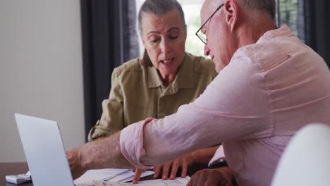pareja de ancianos caucásicos con computadora portátil calculando las finanzas juntos en casa
