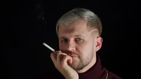 stylish addicted young man with blue eyes in trendy clothes looking at camera, smoking cigarette