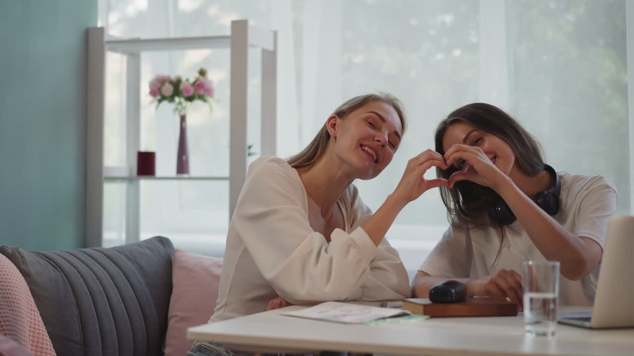 행복한 레즈비언 여성들은 미소 짓는 손가락으로 심장 모양을 만 ⁇ 니다.